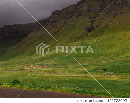 Dramatic Mulafossur waterfall plunging into the ocean with Gasadalur village and cliffs in the background. 132728695