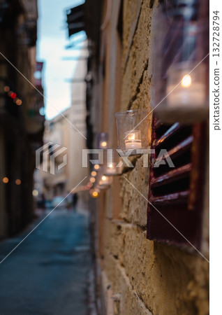 Numerous candles glow on the ancient walls of Birgu during the Birgu by Candlelight festival, creating a warm and magical ambiance 132728794