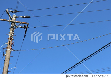 A blue sky landscape with electric wires crossing 132729653