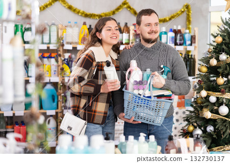 Happy man and woman with full basket choosing presents or something for holidays in household department 132730137