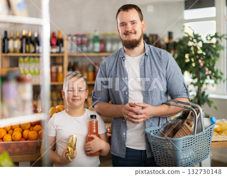 Young dad and tween son choosing food together in supermarket 132730148