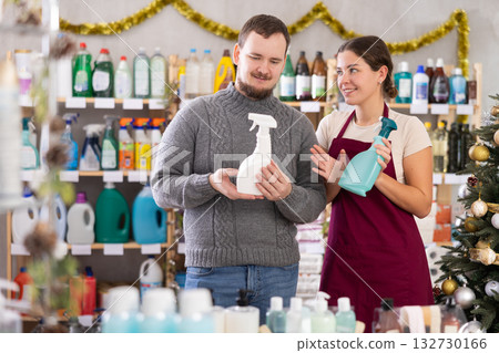Smiling saleswoman offering cleaning sprays to shopper in home care store Smiling saleswoman offering cleaning sprays to shopper in home care store 132730166