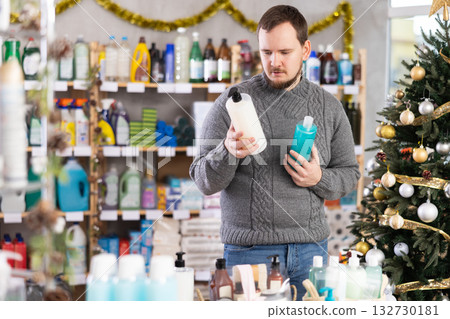 Young man choosing shower gel in store during Christmas holidays Young man choosing shower gel in store during Christmas holidays 132730181