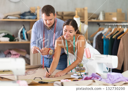 Female tailor sketching pattern with colleague in sewing studio Female tailor sketching pattern with colleague in sewing studio 132730200