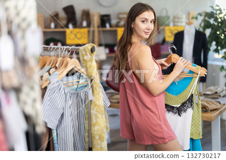Young woman customer making choice and elect something summer clothing in store Young woman customer making choice and elect something summer clothing in store 132730217