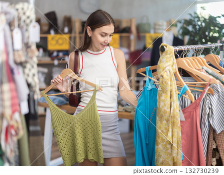 Young woman customer making choice and elect something summer clothing in store 132730239