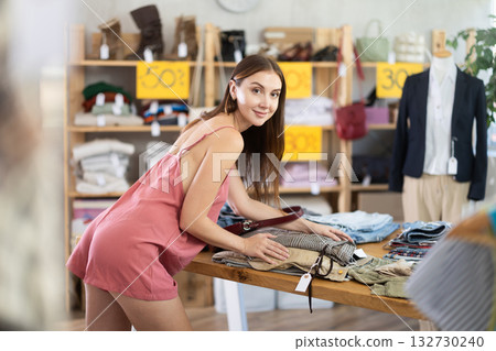 Female shopper choosing trousers in clothing store Female shopper choosing trousers in clothing store 132730240