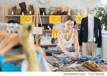 Young woman browsing pants and jeans at outlet store Young woman browsing pants and jeans at outlet store 132730242