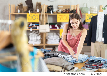 Young woman customer making choice and elect trousers or shorts in store 132730245