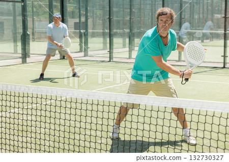 Padel game - man with partners plays on court Padel game - man with partners plays on court 132730327