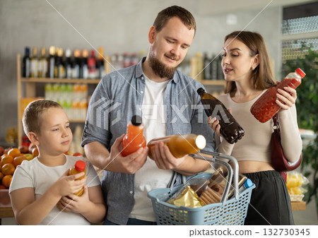 Couple of man and woman with boy choosing juices in grocery Couple of man and woman with boy choosing juices in grocery 132730345