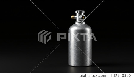 Brushed aluminum gas cylinder with brass fitting against a stark black background 132730390