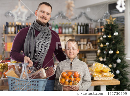 Father and son standing in festive market with chosen products in hands 132730399