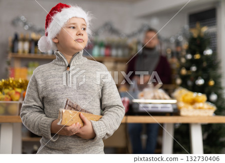 Little boy holding turrons in market with Xmas decoration Little boy holding turrons in market with Xmas decoration 132730406