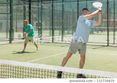 Two adult men playing doubles padel 132730429