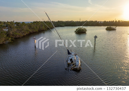 Aerial view of sunken sailboat on shallow bay waters after hurricane in Manasota, Florida 132730437