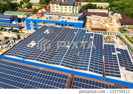 Aerial view of many photo voltaic solar panels mounted of industrial building roof. 132730511