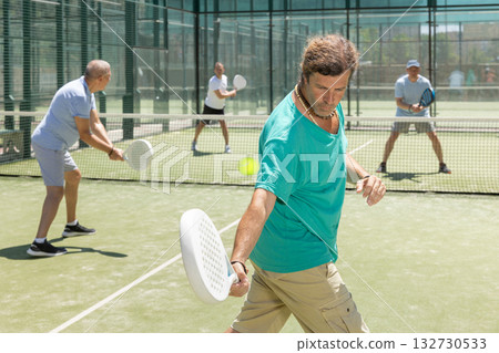 Adult and elderly men playing padel against two men 132730533