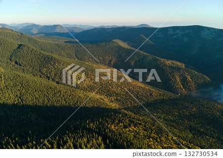 Aerial view of high hills with dark pine forest trees at autumn bright day. Amazing scenery of wild mountain woodland 132730534