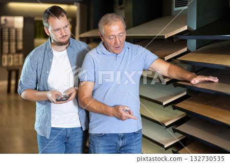 Hardware store salesperson advises an mature customer on buying the best laminate flooring Hardware store salesperson advises an mature customer on buying the best laminate flooring 132730535