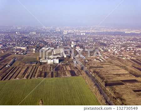 Aerial view of green and plowed fields and city suburbs on sunny dawn. Drone photography. Aerial view of green and plowed fields and city suburbs on sunny dawn. Drone photography. 132730549