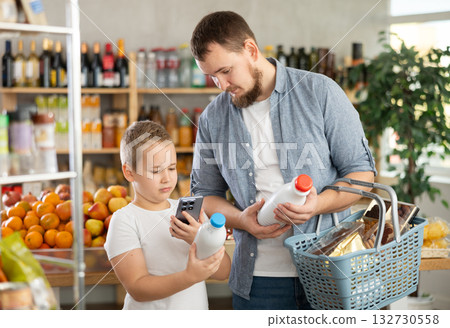 European man with son customer at shop scans QR code on milk bottle using phone camera 132730558