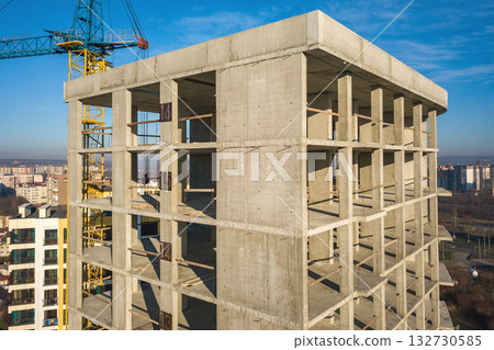 Aerial view of concrete frame of tall apartment building under construction in a city. Aerial view of concrete frame of tall apartment building under construction in a city. 132730585