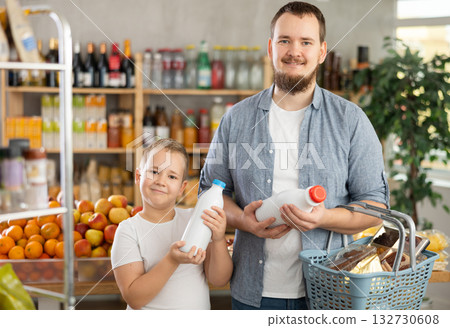 Man with son hold packages bottles and choose consider milk in store Man with son hold packages bottles and choose consider milk in store 132730608
