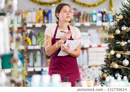 Woman employee with paper, plans to replenish restock stores inventory on Christmas Eve Woman employee with paper, plans to replenish restock stores inventory on Christmas Eve 132730624