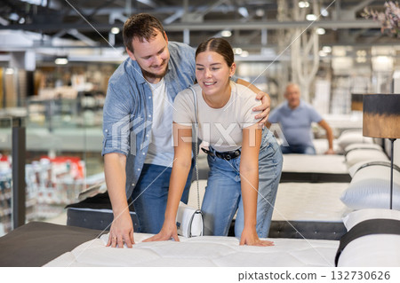 In furniture store, married couple examines orthopedic mattress. 132730626