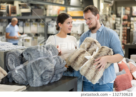 Couple inspects and choose warm soft plaid in store Couple inspects and choose warm soft plaid in store 132730628