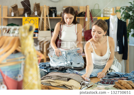 Young women customer making choice and elect trousers or shorts in store 132730651