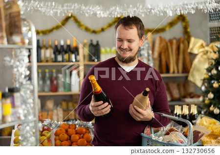 Man pondering choice of wine in festively decorated grocery store 132730656