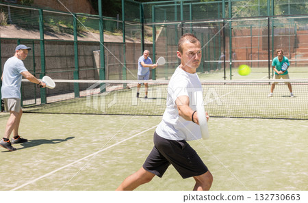 Active man engaged in padel in open-air court of tennis club 132730663