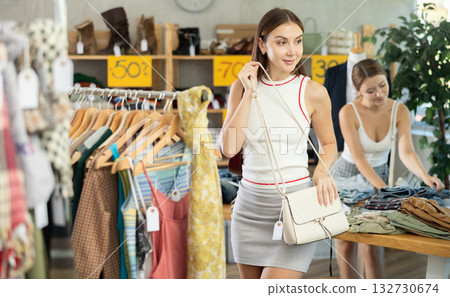 In trading hall, girl choose and buy ladys handbag. Female client choosing something in background 132730674