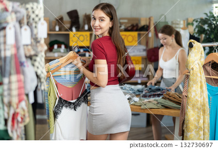Woman chooses T-shirts against the background of a buyer Woman chooses T-shirts against the background of a buyer 132730697