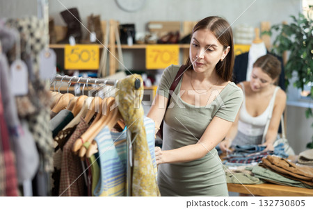 Woman chooses T-shirts against the background of a buyer 132730805