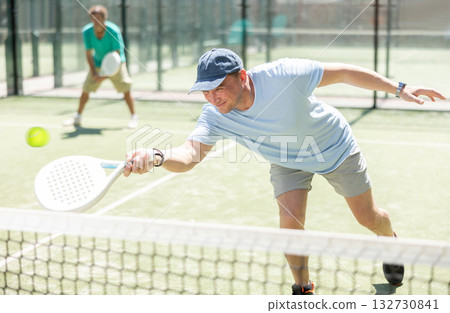 Padel game - man with partners plays on court 132730841
