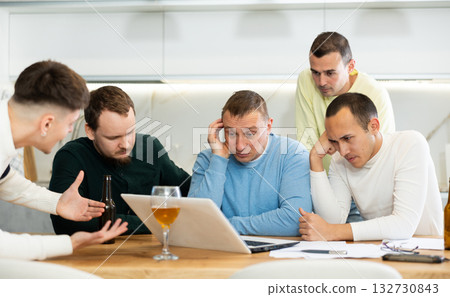 Group of men comforting distressed friend at computer at home 132730843