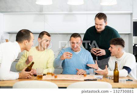 Man drinking shot while losing board game with friends 132730881