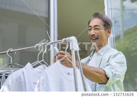 一位 60 多歲的男子正在晾衣服 132731626