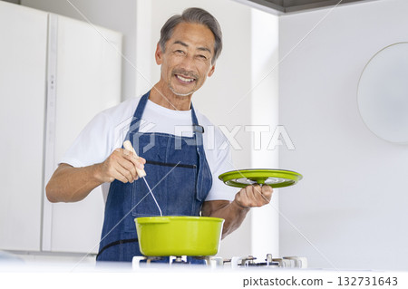 A man in his 60s cooking with a smile while looking at the camera 132731643