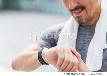 一名男子邊慢跑邊查看他的智慧手錶。 132732559
