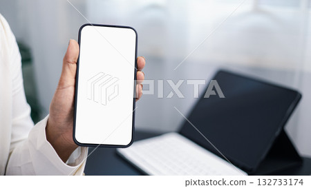Businessman holding smartphone with blank screen mockup in modern office workspace 132733174