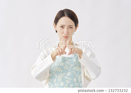 Woman wearing an apron making a cross gesture on a white background Woman wearing an apron making a cross gesture on a white background 132733232