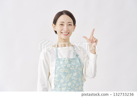 一位身穿圍裙的女子在白色背景上做出勾號手勢。 132733236