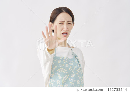 Woman wearing an apron making a stop gesture on a white background 132733244