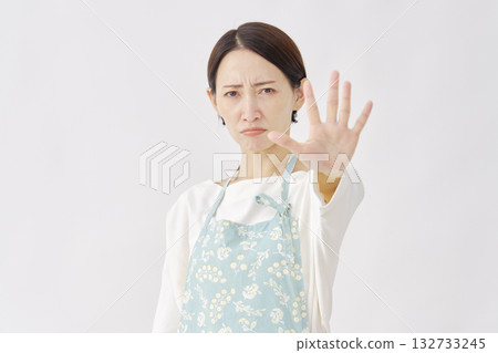 Woman wearing an apron making a stop gesture on a white background 132733245