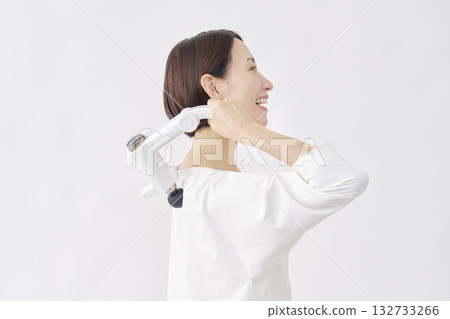 Woman using a massage gun, stiff shoulders, white background Woman using a massage gun, stiff shoulders, white background 132733266