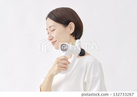 Woman using a massage gun, stiff shoulders, white background Woman using a massage gun, stiff shoulders, white background 132733267